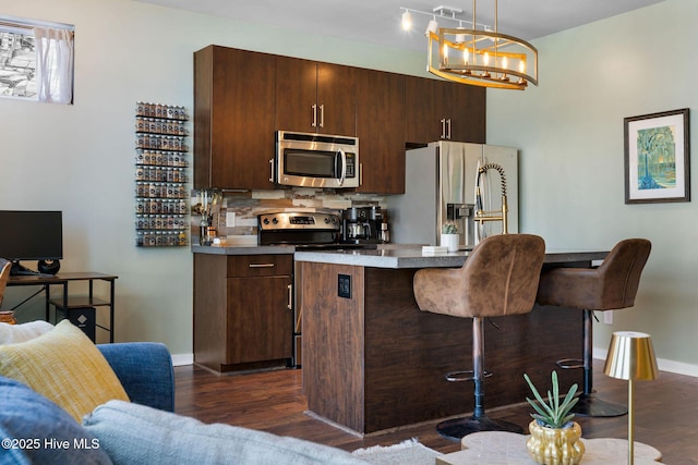 kitchen with dark wood finished floors, a kitchen breakfast bar, appliances with stainless steel finishes, and a kitchen island