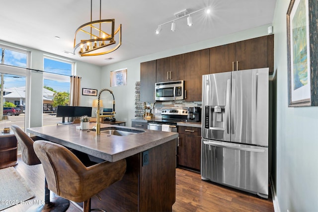 kitchen with dark countertops, dark brown cabinetry, appliances with stainless steel finishes, and dark wood-style floors