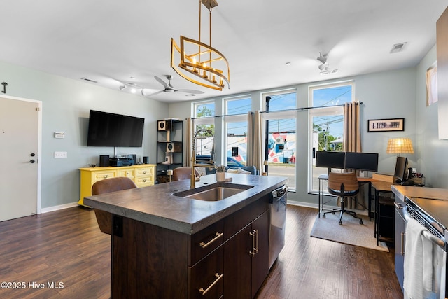 kitchen featuring dark countertops, a sink, dark brown cabinetry, a healthy amount of sunlight, and stainless steel appliances