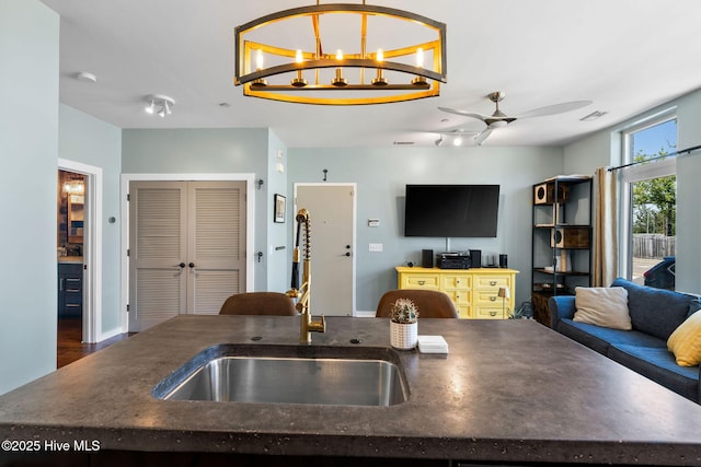 kitchen featuring dark countertops, ceiling fan, a sink, visible vents, and open floor plan