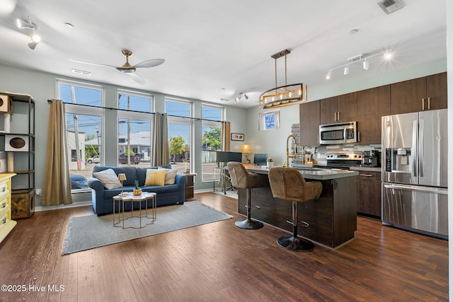 kitchen featuring a sink, stainless steel appliances, a kitchen bar, visible vents, and open floor plan