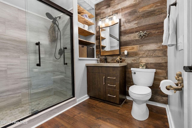 bathroom featuring wood finished floors, a shower stall, wood walls, toilet, and vanity