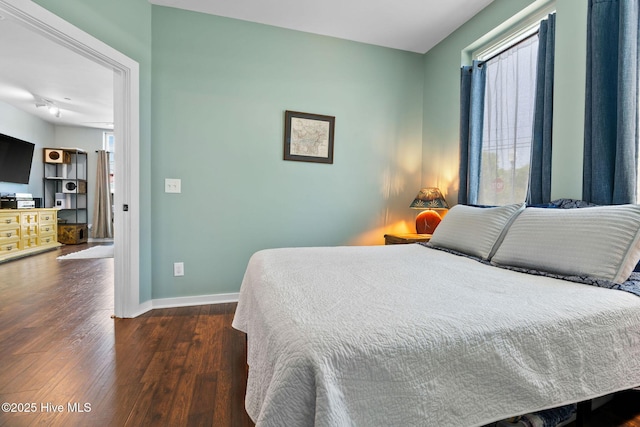 bedroom featuring baseboards and dark wood-style flooring