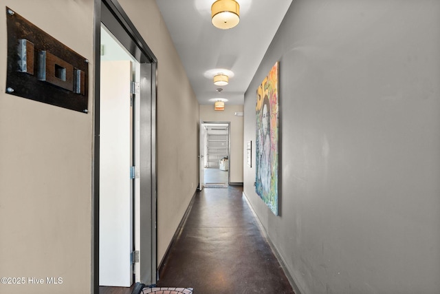 hall with concrete floors and baseboards