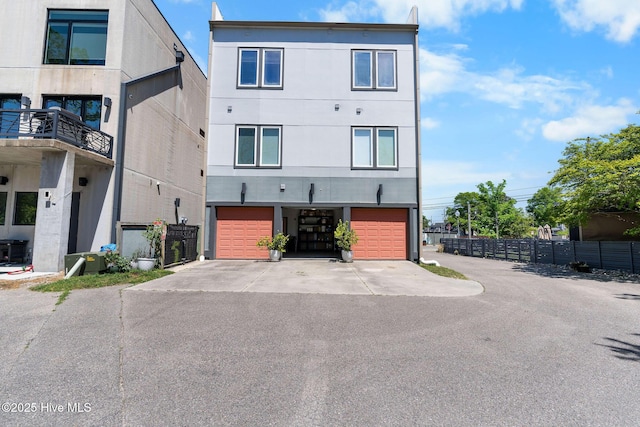 view of front of property featuring fence, aphalt driveway, stucco siding, and an attached garage