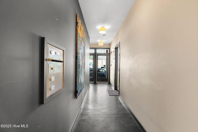 hallway with concrete flooring and baseboards