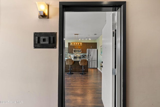 corridor with track lighting and dark wood-type flooring