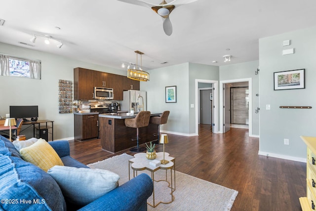 living area with visible vents, a ceiling fan, baseboards, and dark wood finished floors