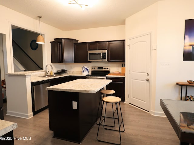 kitchen with stainless steel appliances, dark wood-style floors, a sink, a kitchen bar, and light countertops