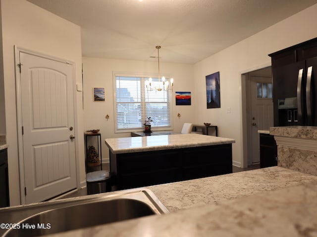 kitchen featuring decorative light fixtures, an inviting chandelier, black fridge, and baseboards