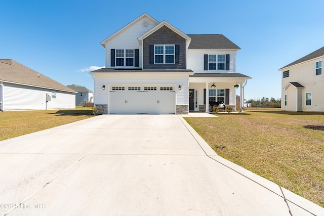 view of front of home with stone siding, an attached garage, covered porch, and a front yard