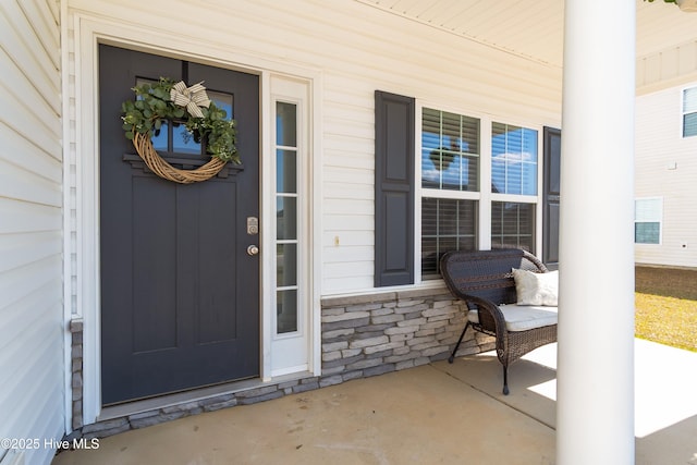 view of exterior entry with a porch and stone siding