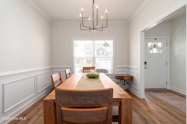 dining room with a wainscoted wall, dark wood-style floors, a notable chandelier, a decorative wall, and ornamental molding