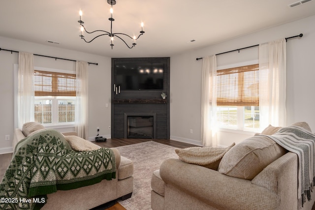 living area with a chandelier, wood finished floors, visible vents, and plenty of natural light