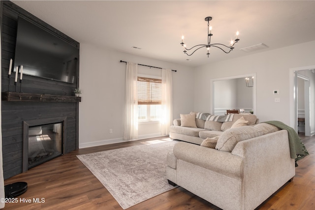 living room with wood finished floors, visible vents, and an inviting chandelier