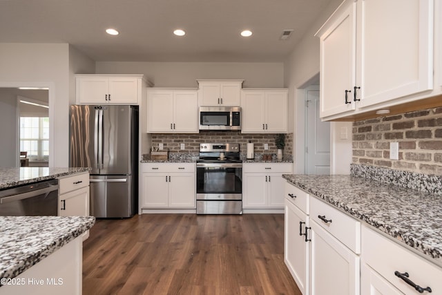 kitchen featuring decorative backsplash, appliances with stainless steel finishes, white cabinetry, and visible vents