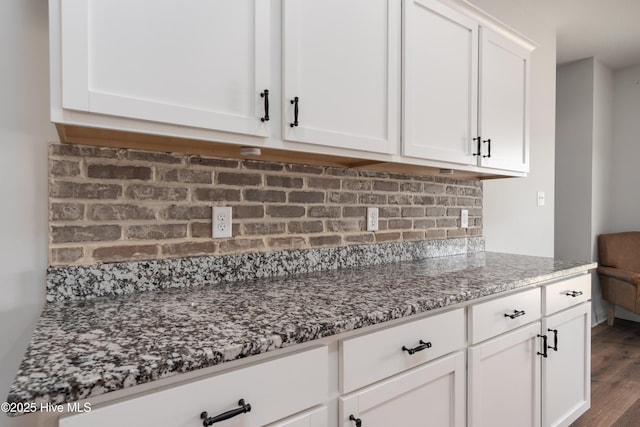 kitchen featuring backsplash, white cabinets, dark stone counters, and dark wood-style flooring
