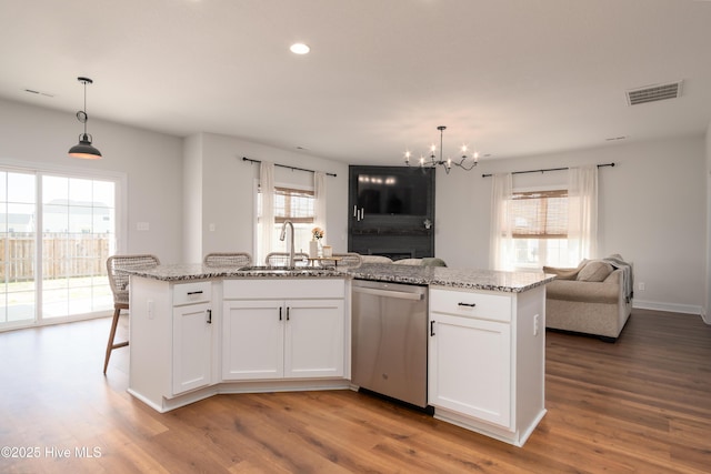 kitchen featuring stainless steel dishwasher, a sink, open floor plan, a chandelier, and visible vents