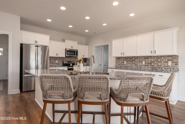 kitchen with stainless steel appliances, recessed lighting, light stone counters, and tasteful backsplash