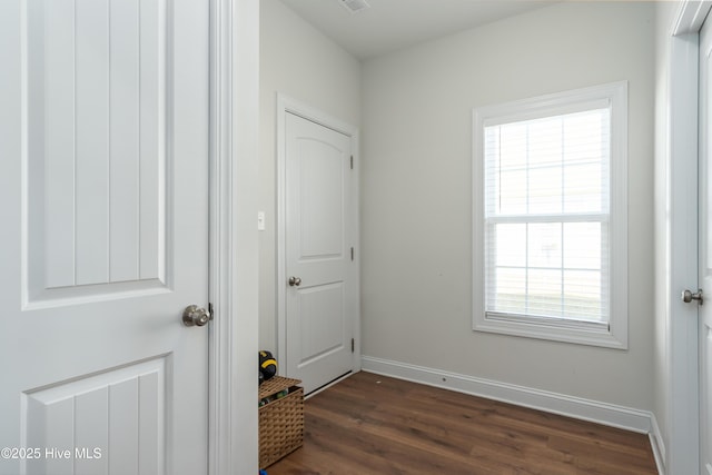 doorway with dark wood finished floors, visible vents, and baseboards
