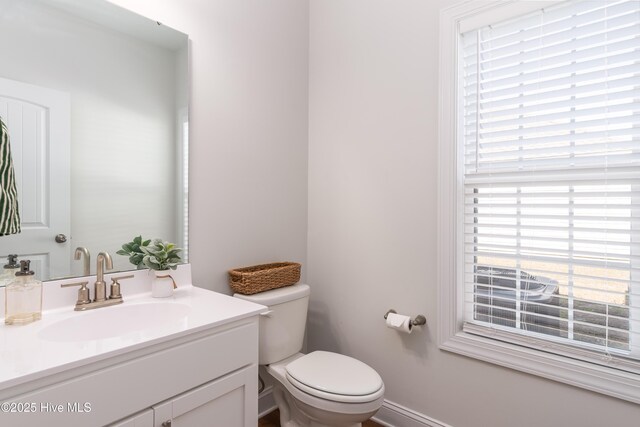half bath featuring toilet, vanity, and baseboards