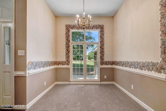 unfurnished room with a chandelier, baseboards, and carpet floors