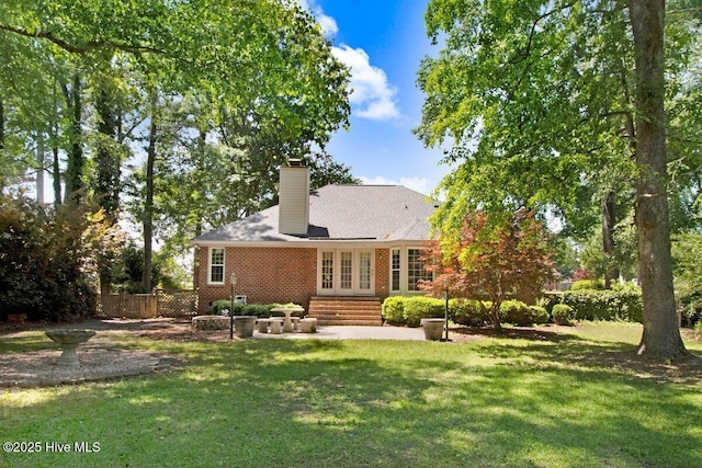 rear view of house featuring french doors, brick siding, a patio, and a chimney