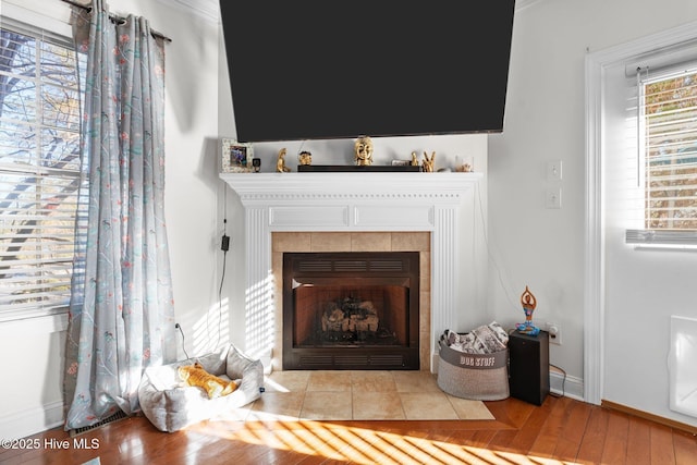 details with baseboards, wood finished floors, and a tile fireplace