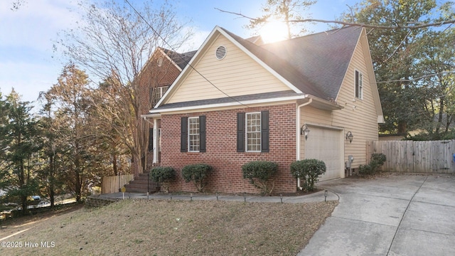 view of home's exterior with an attached garage, concrete driveway, fence, and brick siding