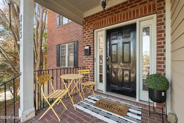 entrance to property featuring brick siding and covered porch