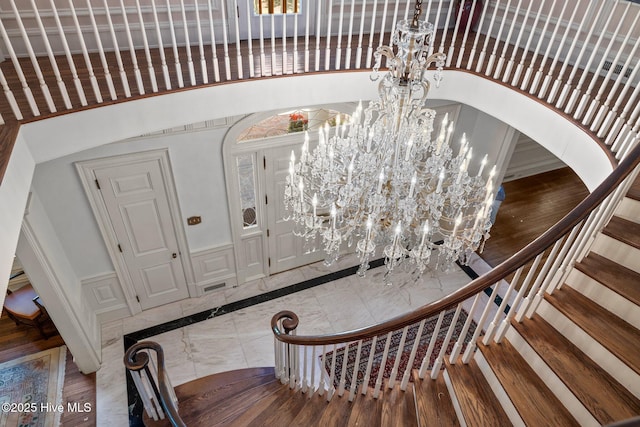 130 Harbour Dr, Hubert, NC 28539 - stairs with a chandelier, a decorative wall, a wainscoted wall, inlaid floor details, and arched walkways