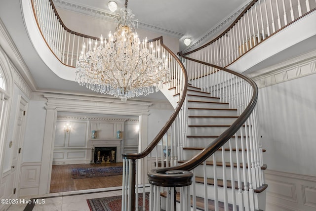 130 Harbour Dr, Hubert, NC 28539 - staircase featuring a decorative wall, a fireplace, crown molding, marble finish flooring, and a chandelier