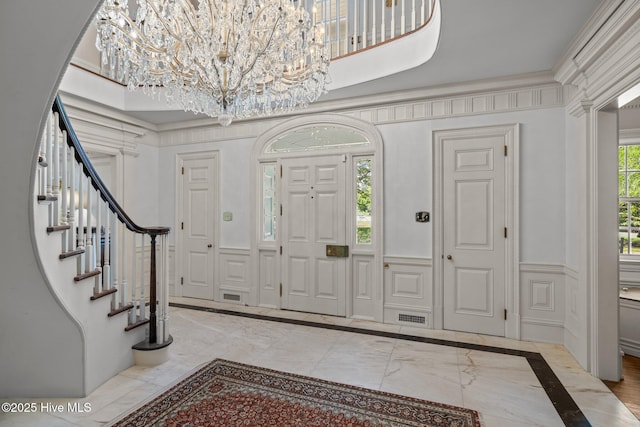 130 Harbour Dr, Hubert, NC 28539 - entryway with a chandelier, inlaid floor details, stairs, a decorative wall, and a wainscoted wall
