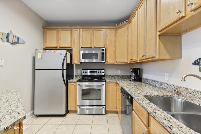 kitchen featuring light brown cabinets, a sink, light tile patterned flooring, stainless steel appliances, and light stone countertops