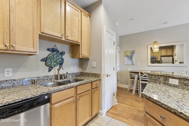 kitchen with light stone counters, stainless steel appliances, light brown cabinets, a sink, and pendant lighting
