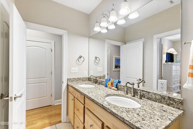 bathroom with double vanity, visible vents, wood finished floors, and a sink