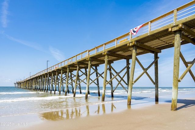view of dock featuring a beach view, a pier, and a water view