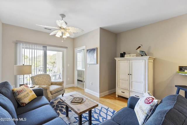 living room with light wood-type flooring, ceiling fan, radiator, baseboards, and visible vents