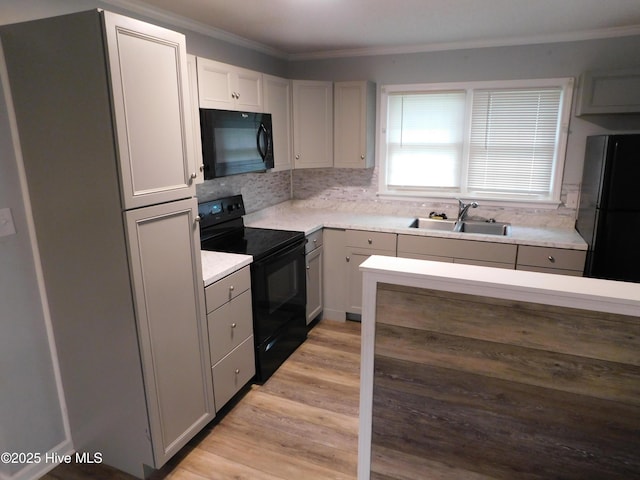 17261 Harvell Ln, Laurinburg, NC 28352 - kitchen featuring black appliances, a sink, crown molding, tasteful backsplash, and light wood-style floors