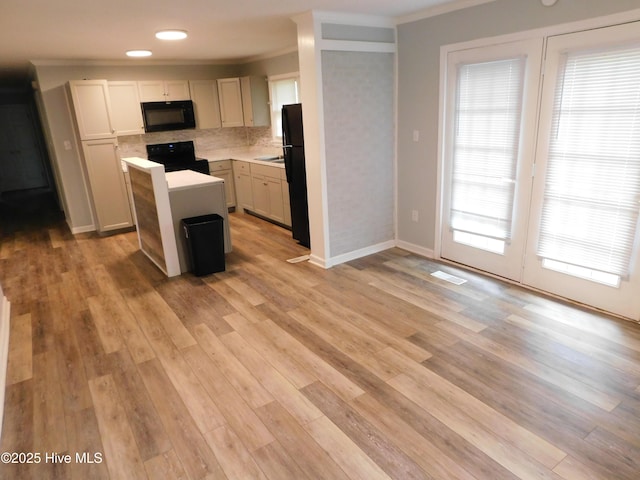 17261 Harvell Ln, Laurinburg, NC 28352 - kitchen with black appliances, a kitchen island, crown molding, light countertops, and plenty of natural light