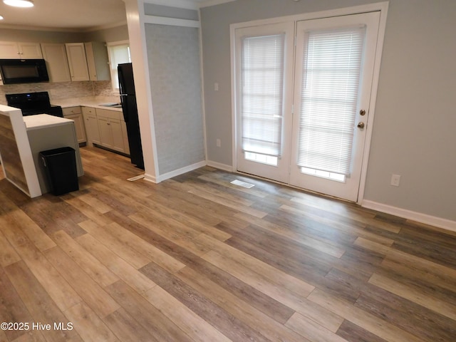 17261 Harvell Ln, Laurinburg, NC 28352 - kitchen with black appliances, light countertops, light wood finished floors, baseboards, and ornamental molding