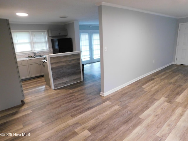 17261 Harvell Ln, Laurinburg, NC 28352 - kitchen with freestanding refrigerator, crown molding, a sink, light countertops, and light wood-style flooring