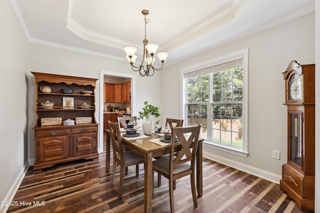 dining area with a chandelier, dark wood-style floors, crown molding, a tray ceiling, and baseboards