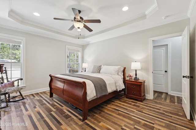bedroom with a tray ceiling, wood finished floors, ornamental molding, recessed lighting, and baseboards