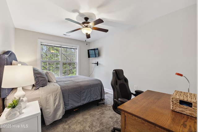 carpeted bedroom with an office area, ceiling fan, and baseboards