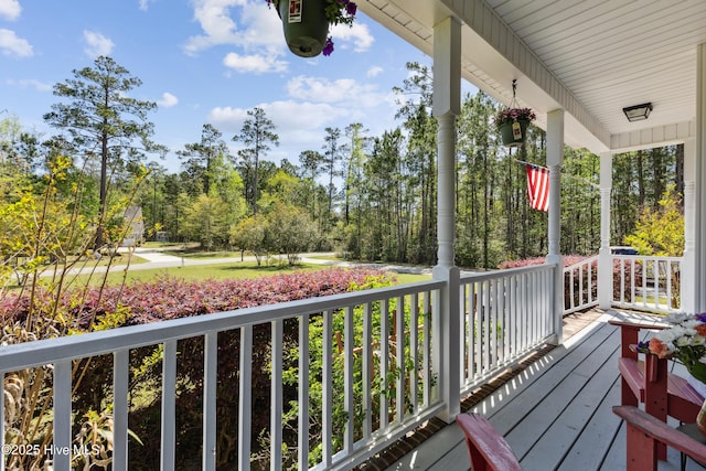 deck with covered porch and view of scattered trees