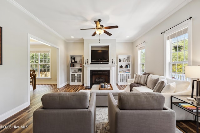 living room featuring crown molding, ceiling fan, wood finished floors, baseboards, and a high end fireplace