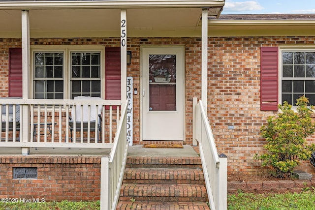 property entrance with brick siding and covered porch