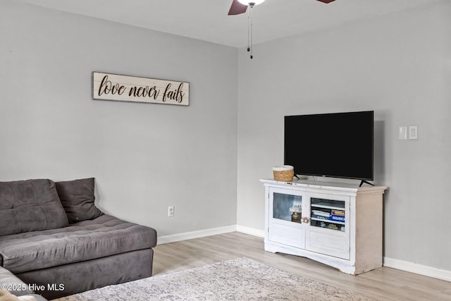 living room with a ceiling fan, baseboards, and wood finished floors