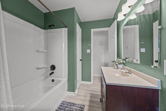 full bathroom featuring baseboards, wood finished floors, shower / bath combo with shower curtain, and vanity